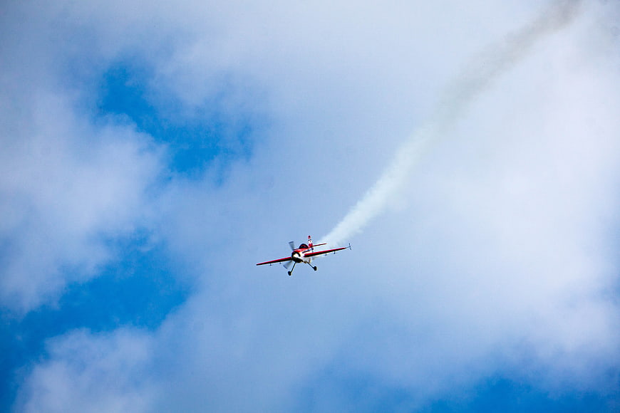 Red Aerobatic Plane Flying with Smoke Trail in Blue Sky