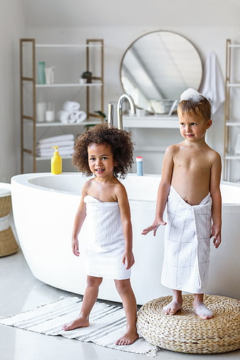 Two happy children wrapped in towels after bath time