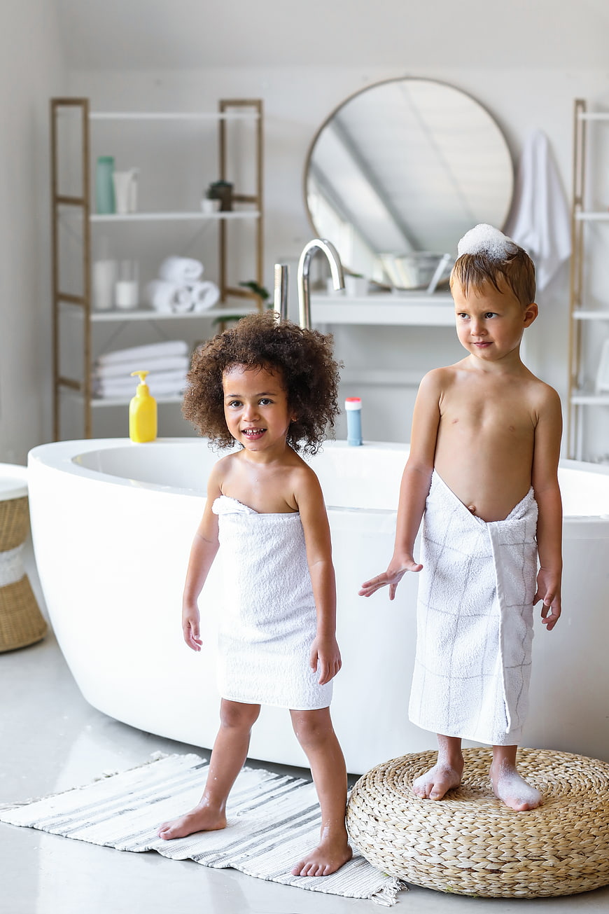 Two happy children wrapped in towels after bath time