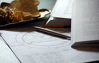 Astrology chart with pen and book on desk