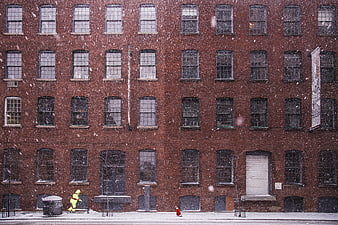 Snowy Urban Street Scene with Brick Building and Firefighter