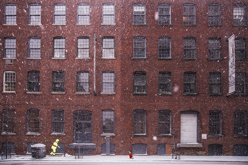 Snowy Urban Street Scene with Brick Building and Firefighter