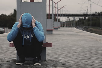 Lonely man in blue hoodie sitting at empty train station
