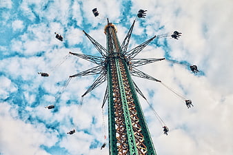 Low angle view of tall swing ride against blue sky