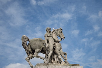Stone statue of man and horse against blue sky