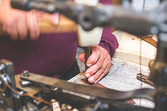 Close-up of hands using a chisel and hammer on leather