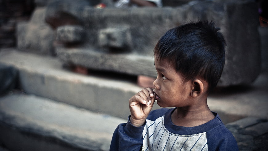 Profile of a young boy looking away with hand near mouth