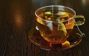 Steaming hot tea in a clear glass cup on a wooden table