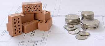 Construction bricks and silver coins on architectural blueprint