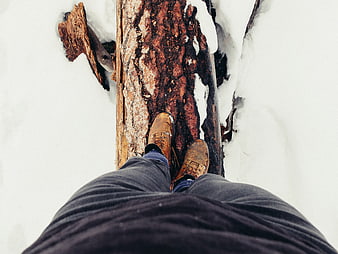 First-person view of boots walking on a log in snow