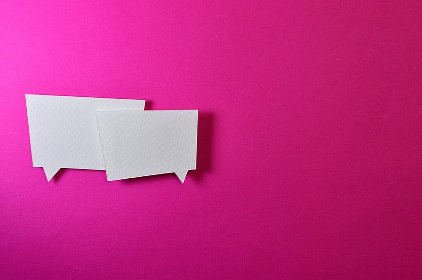 Two white paper speech bubbles on a vibrant magenta background