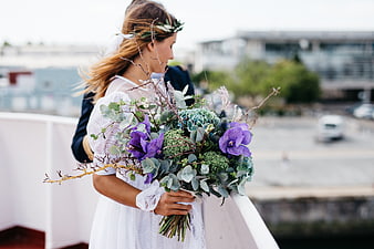 Bride holding purple and green bouquet on rooftop