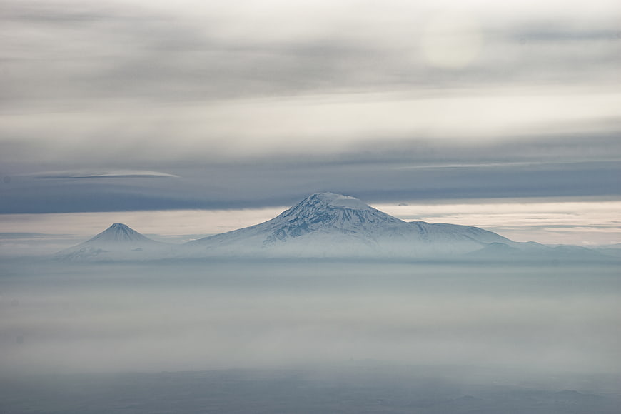 Snowy mountain peaks rising above sea of clouds