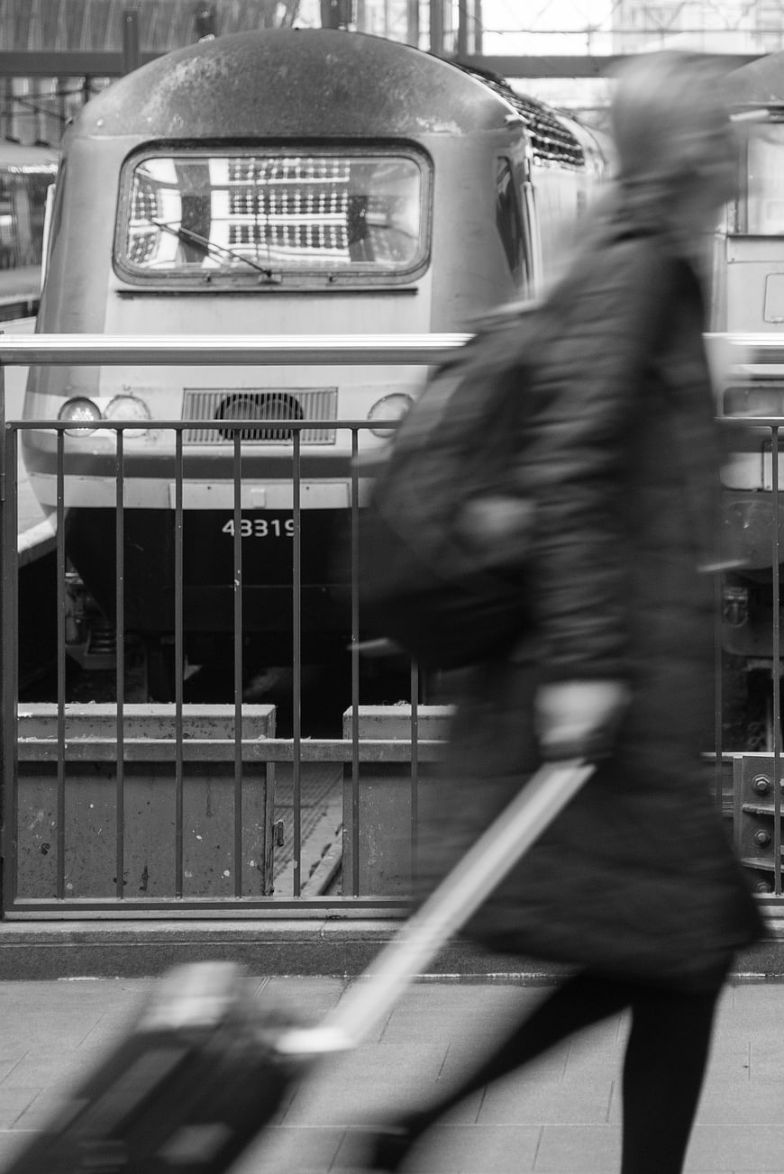 Blurred traveler with suitcase walking past train station