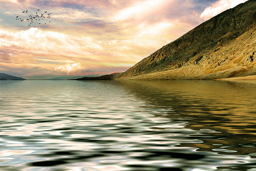 Serene Mountain Lake at Sunset with Birds Flying