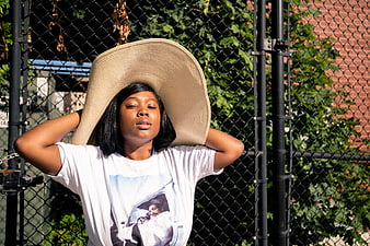 Woman in Oversized Straw Hat Relaxing by Fence