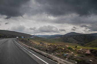 Winding Mountain Road Under Dramatic Stormy Clouds
