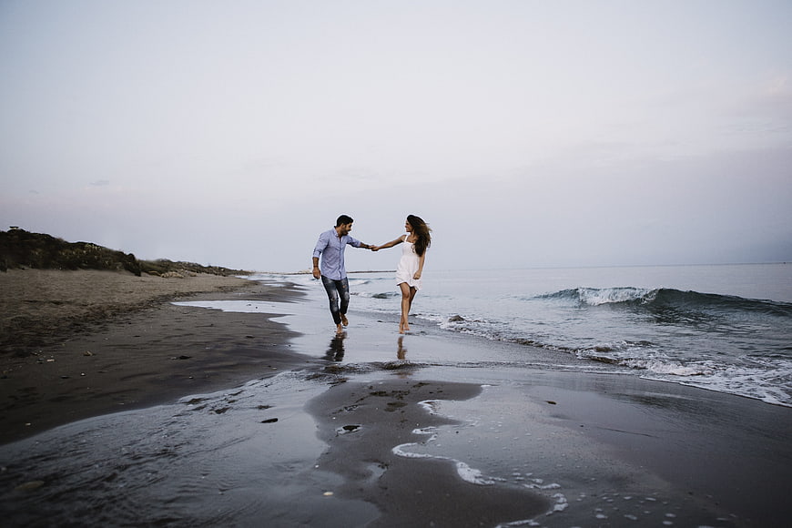 Couple holding hands walking on wet sand at a secluded beach