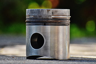 Close-up of used engine piston on asphalt