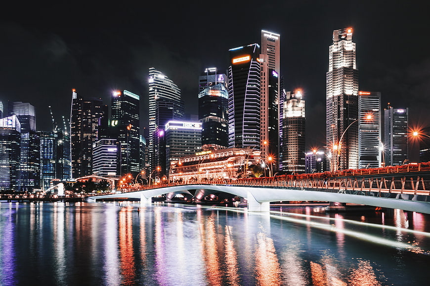 Singapore skyline at night with bridge and water reflections