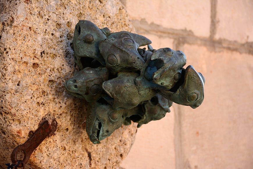 Bronze frog sculpture cluster on textured stone wall