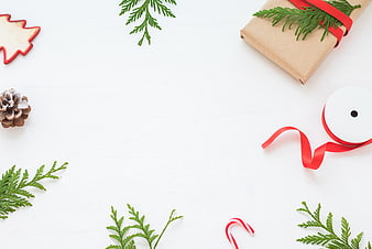 Christmas flat lay with gift, pine branches, and red ribbon on white background