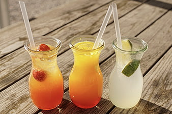 Three Refreshing Fruit Cocktails In Glass Bottles On Rustic Wooden Table