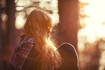 Woman with long hair in forest at sunset