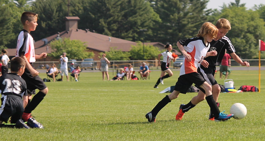 Youth Soccer Boys Competing for Ball on Grass Field