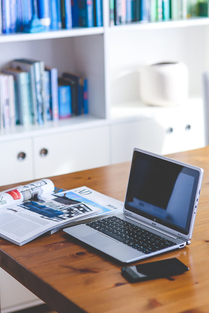 Modern workspace with laptop, magazine, and smartphone on wooden desk