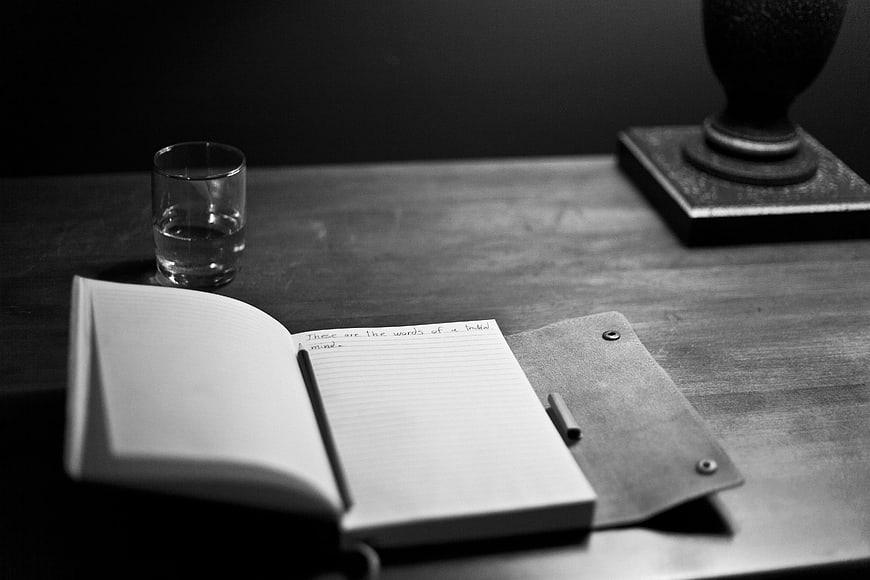 Black and white notebook with handwritten text on wooden desk