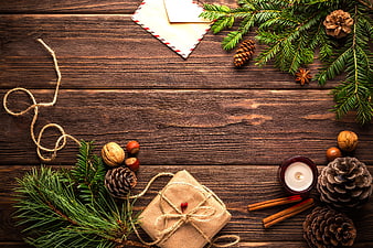 Christmas flat lay with pine branches, gift, and candle on wood