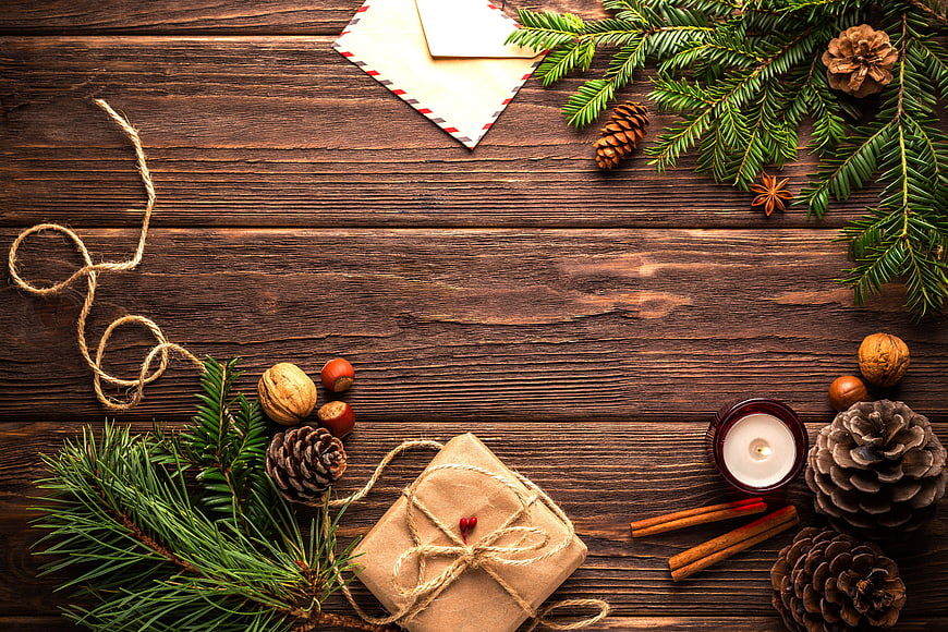Christmas flat lay with pine branches, gift, and candle on wood