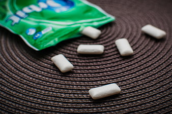 White chewing gum pieces scattered on textured brown mat