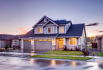 Modern suburban home exterior at dusk with wet driveway