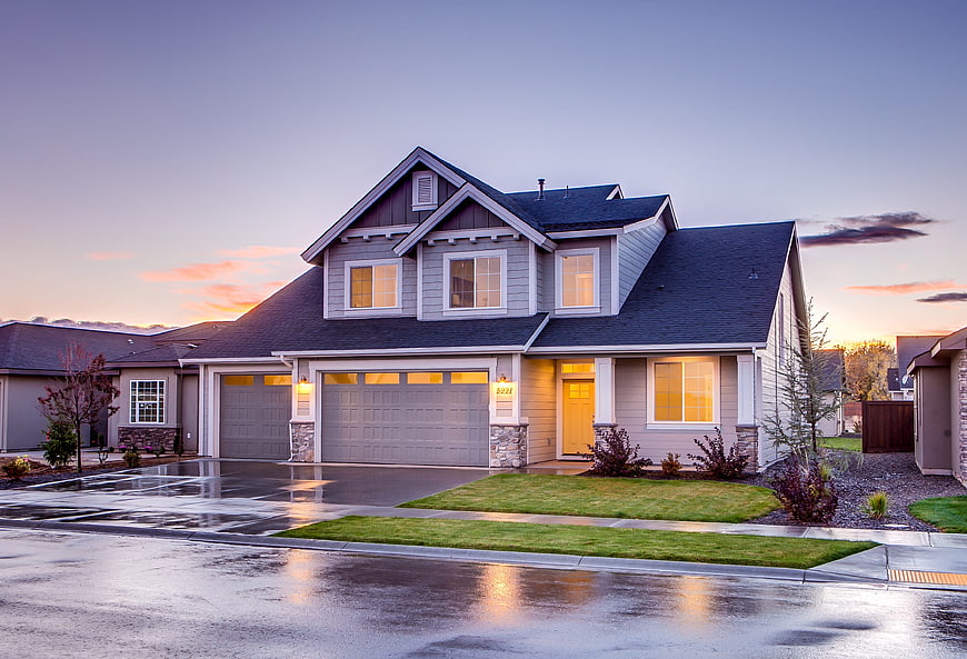 Modern suburban home exterior at dusk with wet driveway