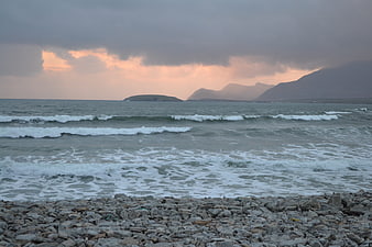 Dramatic Sunset Over Rocky Beach and Ocean Waves