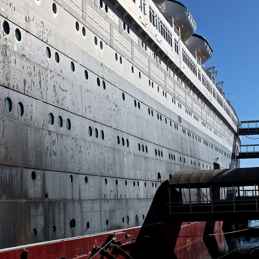 Side view of massive white cruise ship hull at dock