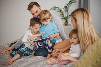 Happy family using tablet together on bed at home