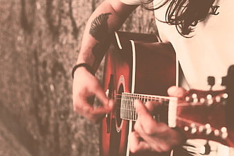 Close-up of musician playing acoustic guitar with tattoo