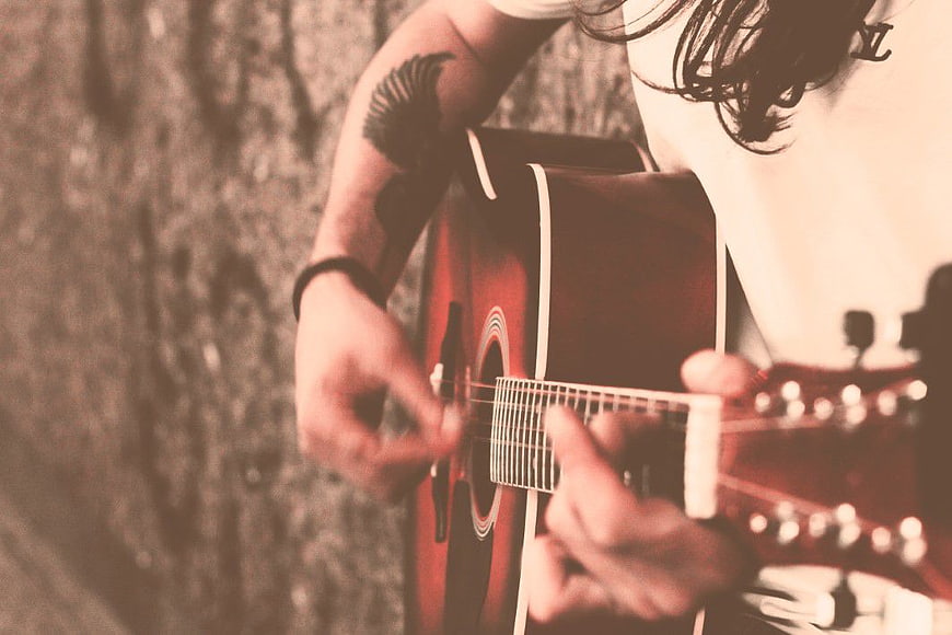 Close-up of musician playing acoustic guitar with tattoo