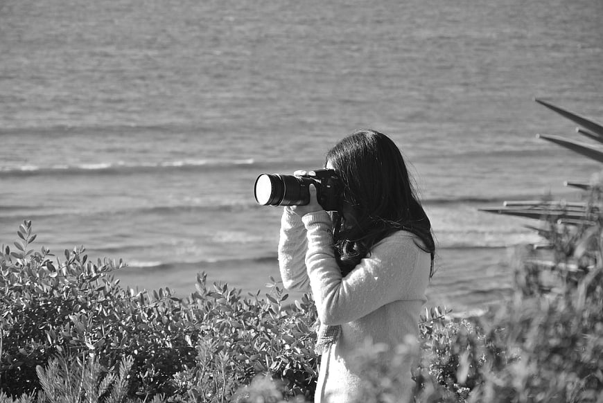 Woman Photographing Ocean with DSLR Camera
