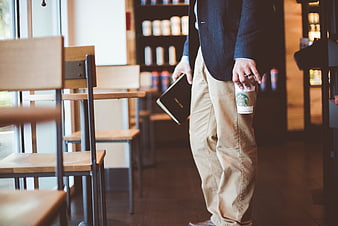 Businessman holding coffee cup and notebook in cafe