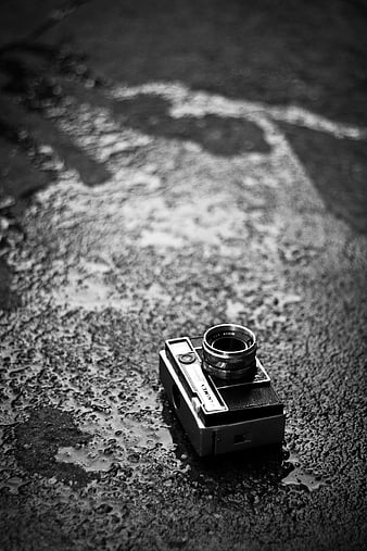 Vintage black and white camera on wet asphalt