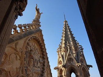 Gothic Cathedral Spire and Sculpture Detail Against Blue Sky