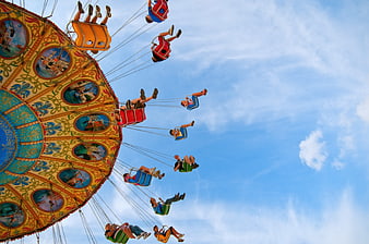 Low angle view of colorful carnival swing ride against blue sky
