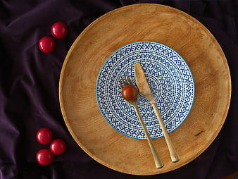 Top view of blue patterned plate with cutlery and tomatoes on wood