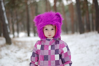 Cute Girl in Pink Winter Jacket and Fuzzy Hat in Snowy Forest