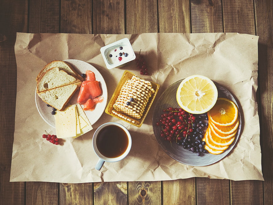 Healthy breakfast spread with coffee, fruit, and cheese on wood