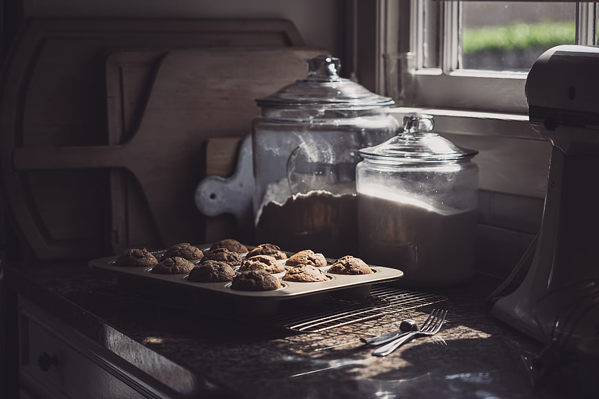 Freshly baked muffins on kitchen counter with flour jars